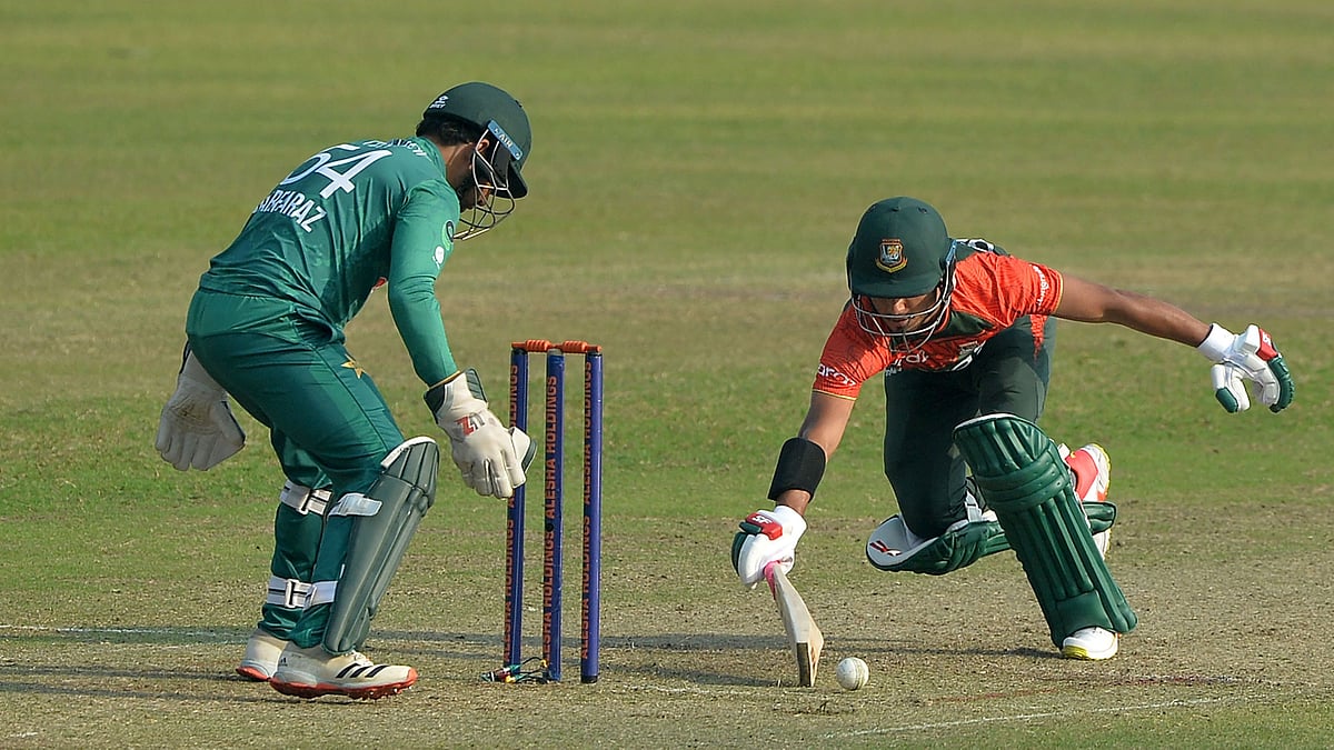 Bangladesh's Afif Hossain (R) tries to stop a ball from hitting the stumps during the third Twenty20 cricket match between Bangladesh and Pakistan at Sher-E-Bangla National Cricket Stadium in Dhaka on 22 November 2021.