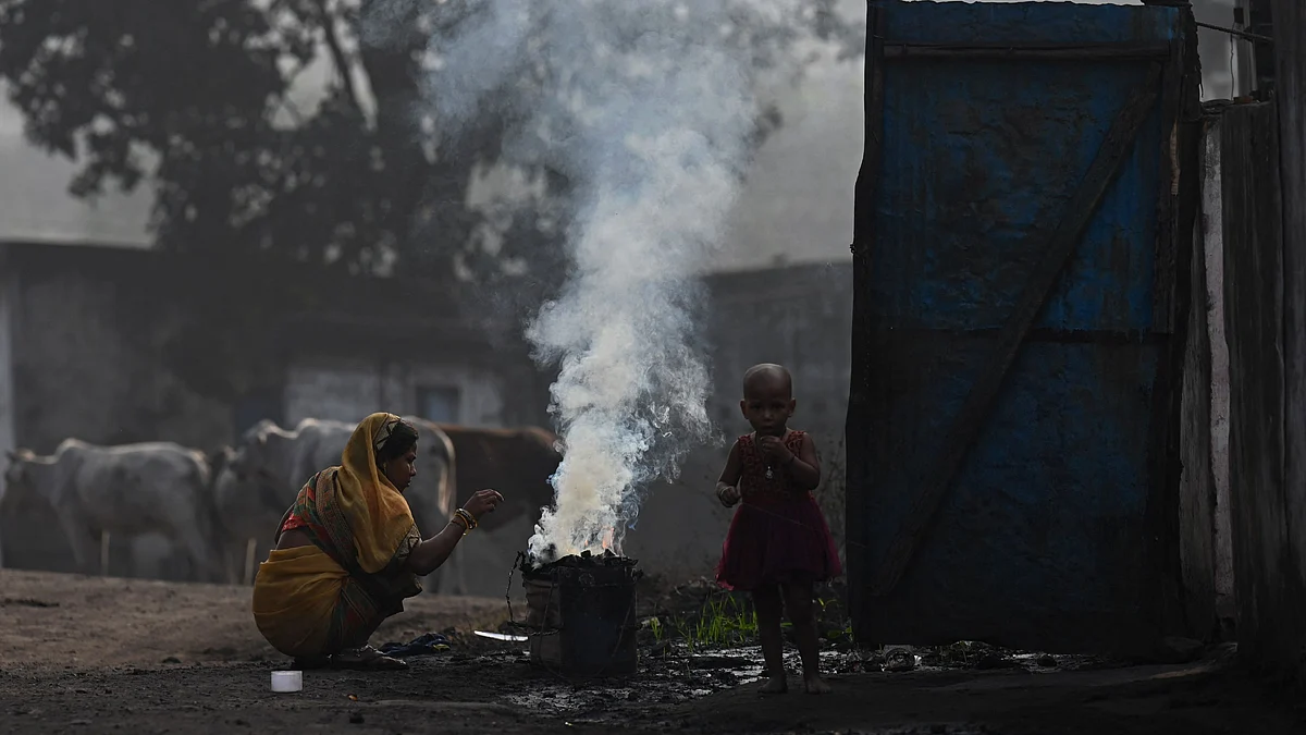In this file photo taken on 18 November, 2021, a woman along with her child burns coal for domestic use at Singrauli in India's Madhya Pradesh state