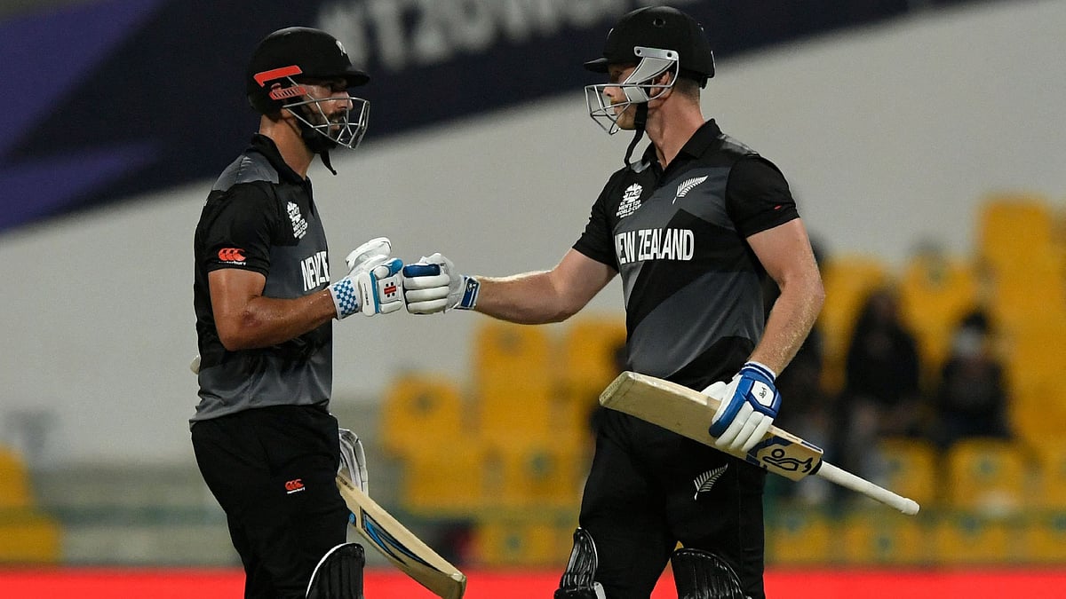 New Zealand's James Neesham (R) and Daryl Mitchell bump their fists after a six during the ICC men’s Twenty20 World Cup semi-final match between England and New Zealand at the Sheikh Zayed Cricket Stadium in Abu Dhabi on 10 November, 2021