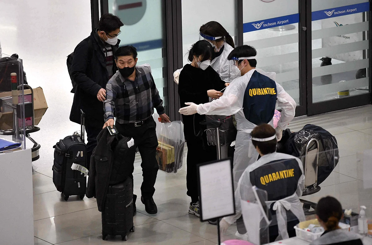 Staff members wearing protective equipment guide travellers at the arrival hall of Incheon International Airport on 30 November, 2021, amid growing concerns about the Omicron Covid-19 variant