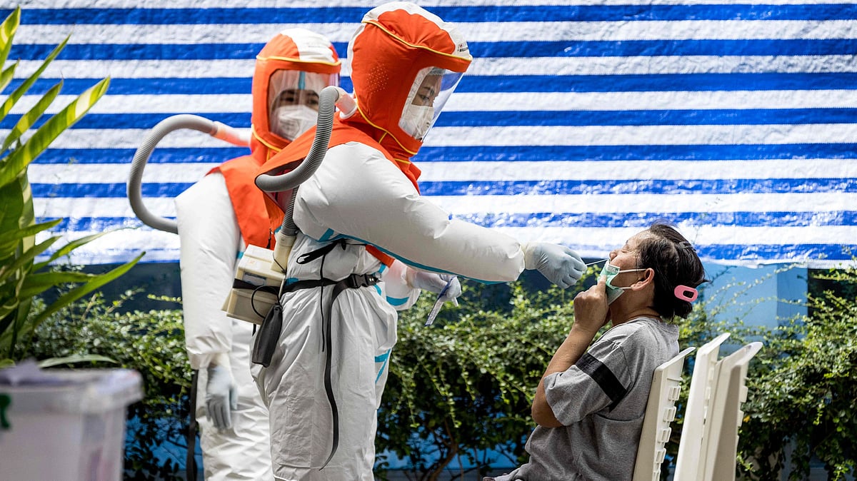 A health worker wearing personal protective equipment (PPE) administers a Covid-19 coronavirus nasal swab during a round of testing of workers outside a market in Bangkok on 4 September, 2021