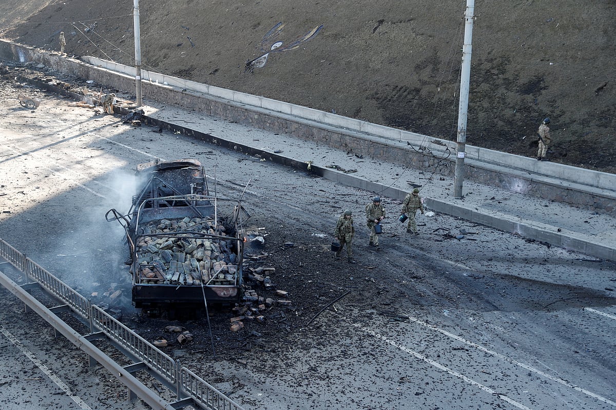 Ukrainian servicemen walk by a damaged vehicle, at the site of fighting with Russian troops, after Russia launched a massive military operation against Ukraine, in Kyiv, Ukraine 26 February 2022.
