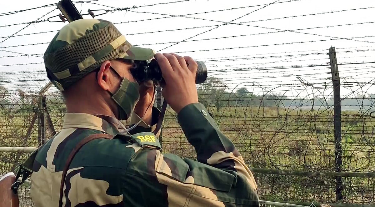 A Border Security Force (BSF) personnel looks through the binoculars at the 'Anti Cut-Anti Climb' fence introduced along the India-Bangladesh border on 29 January 2022