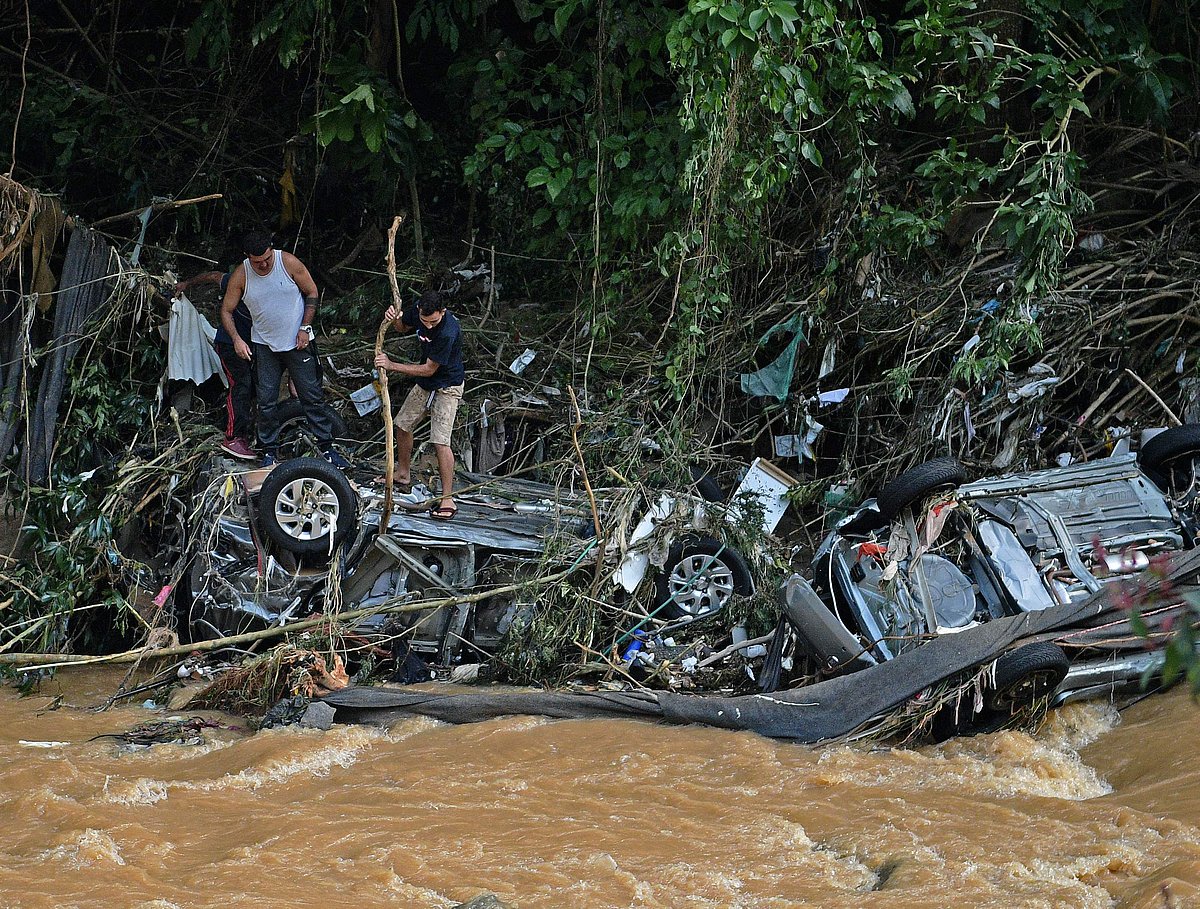People try to rescue items from cars destroyed by a flash flood in Petropolis, Brazil on 16 February, 2022