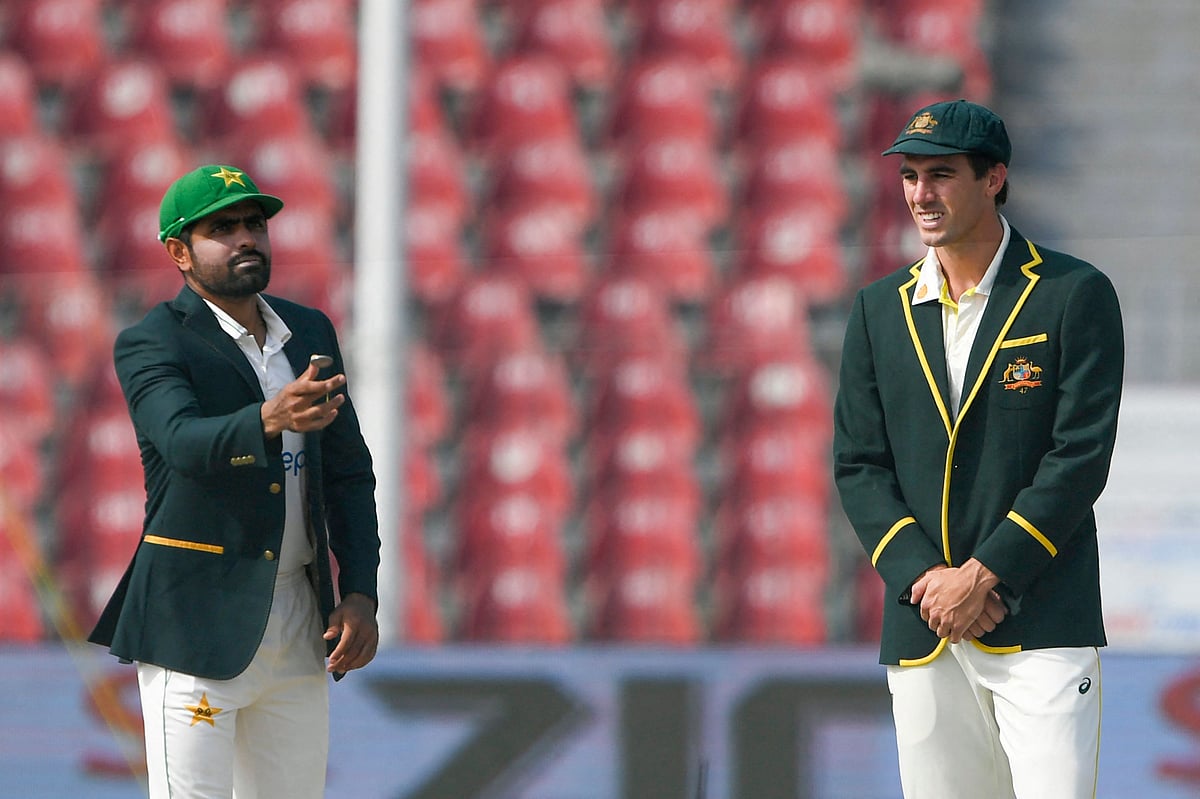 Pakistan's captain Babar Azam (L) tosses a coin as his Australian counterpart Pat Cummins looks on before the start of the first day of the third cricket Test match between Pakistan and Australia at the Gaddafi Cricket Stadium in Lahore on 21 March, 2022