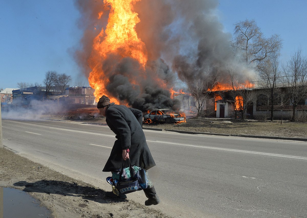 An elderly man walks as fire engulfs a gas station following an artillery attack on the 30th day of the Russian invasion of Ukraine in the northeastern city of Kharkiv on 25 March, 2022