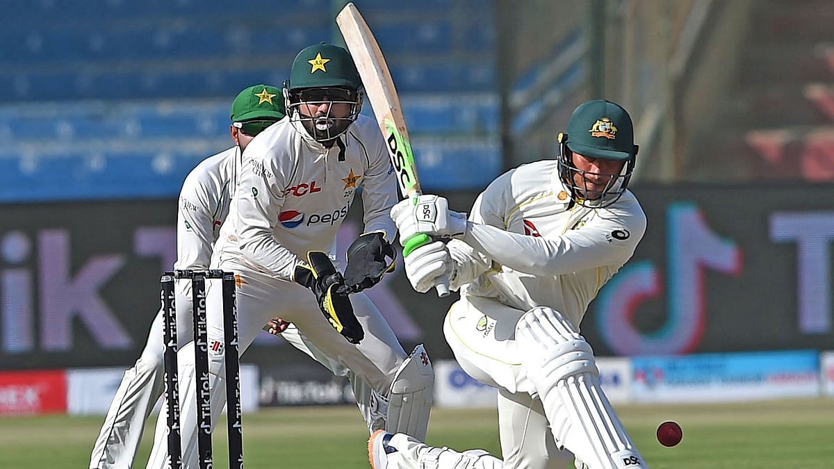 Australia's Usman Khawaja (R) plays a shot as Pakistan's wicketkeeper Mohammad Rizwan watches during the first day of the second Test cricket match between Pakistan and Australia at the National Cricket Stadium in Karachi on 12 March 2022.
