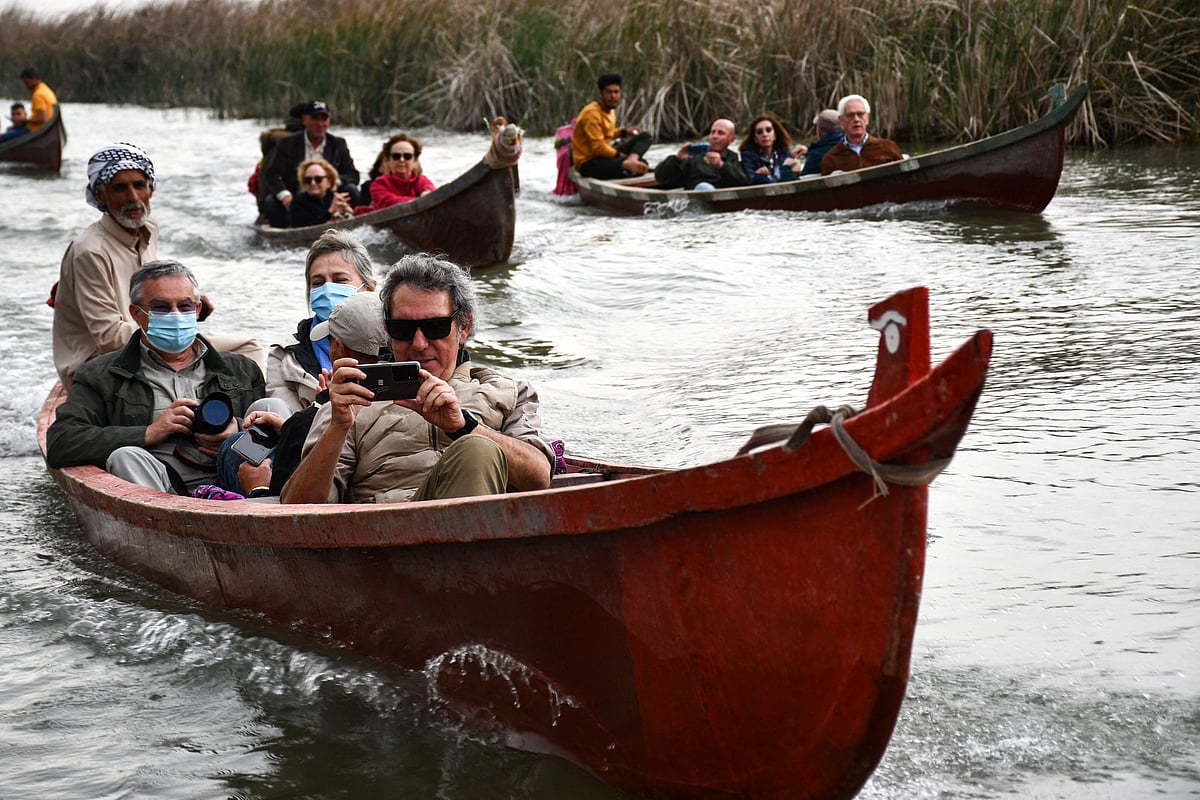 Spanish visitors of the Marshes of Jabayesh in southern Iraq ride boats as they tour the area, on 25 February, 2022