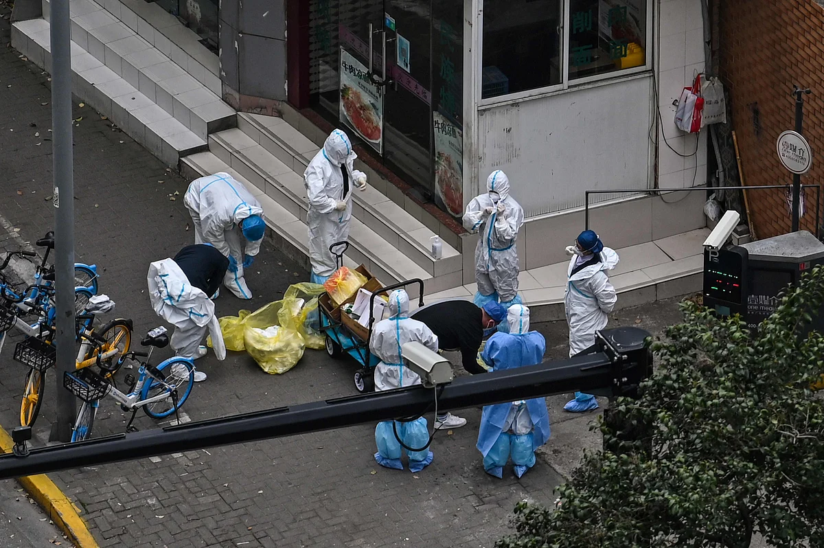 Workers take off their protective gear next to the entrance of a neighbourhood during the second stage of a pandemic lockdown in Jing' an district in Shanghai on 5 April, 2022