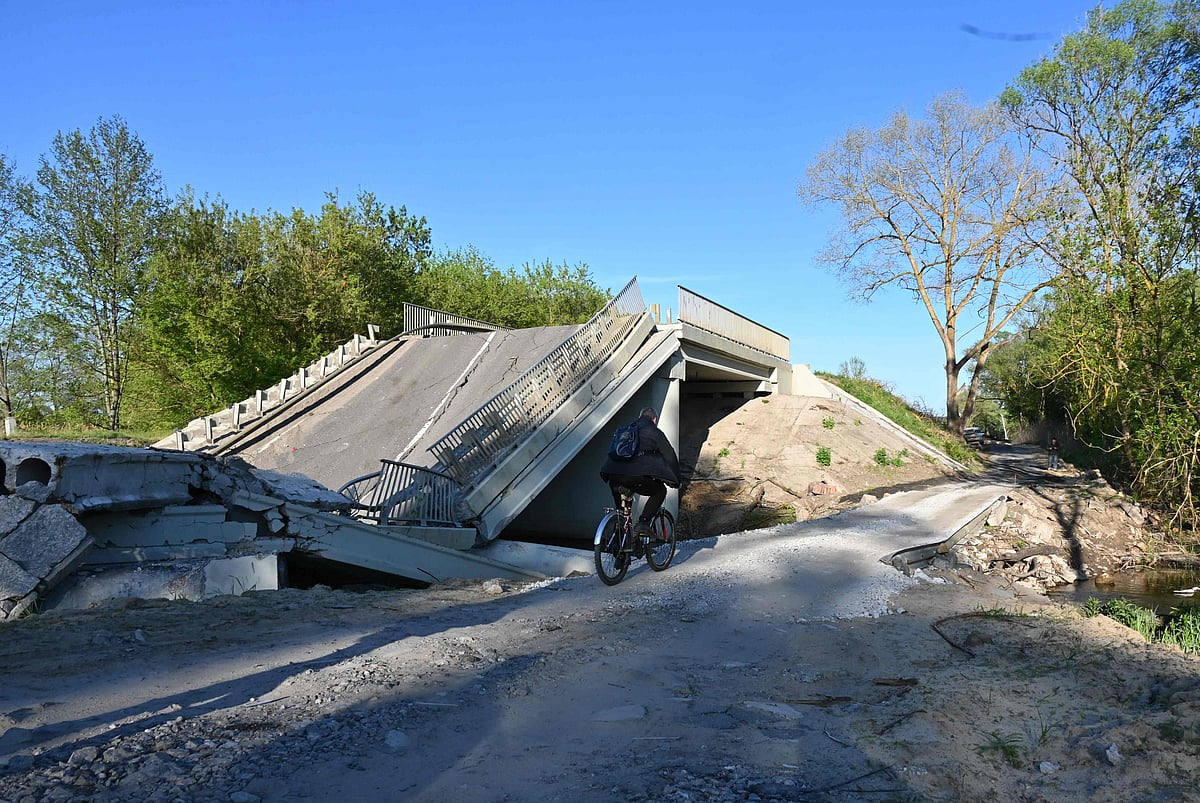 A man rides his bicycle next to a destroyed bridge near Pechenegi village in the Kharkiv region on 5 May 2022, amid the Russian invasion of Ukraine