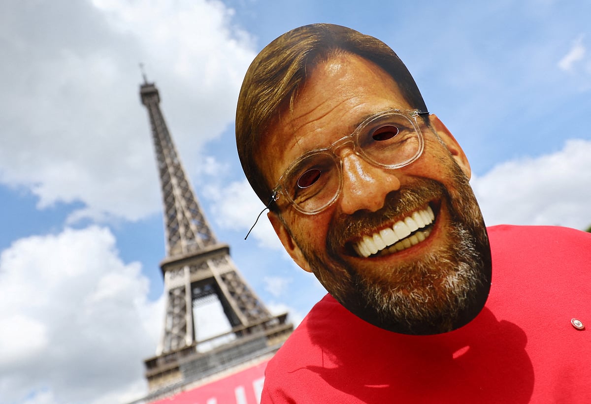 A Liverpool fan is pictured wearing a mask depicting manager Jurgen Klopp in front of the Eiffel Tower ahead of the Champions League final 28 May, 2022