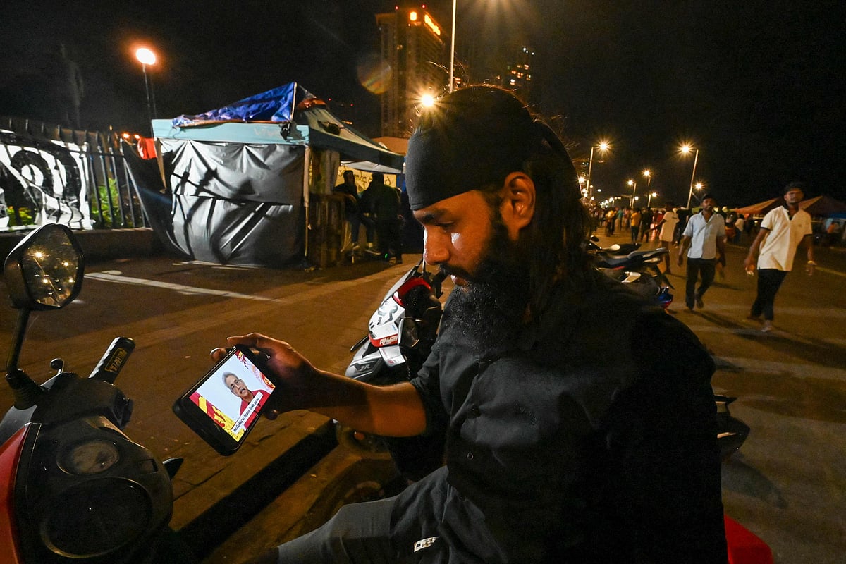 A protester holds a mobile phone while watching an address to the nation by Sri Lanka's President Gotabaya Rajapaksa near the president's office in Colombo on 11 May, 2022