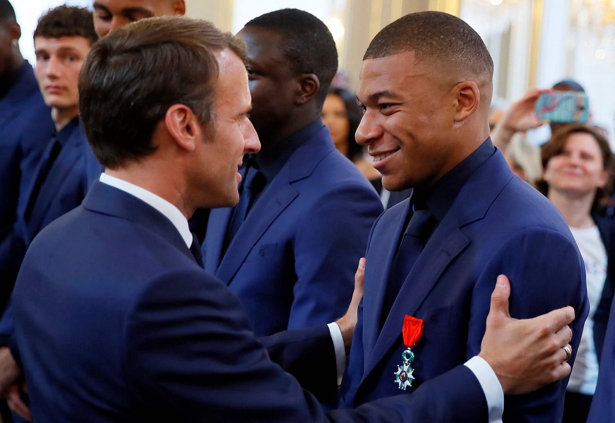 France's president Emmanuel Macron (L) embraces France's forward Kylian Mbappe (R) during a ceremony to award French 2018 football World Cup winners