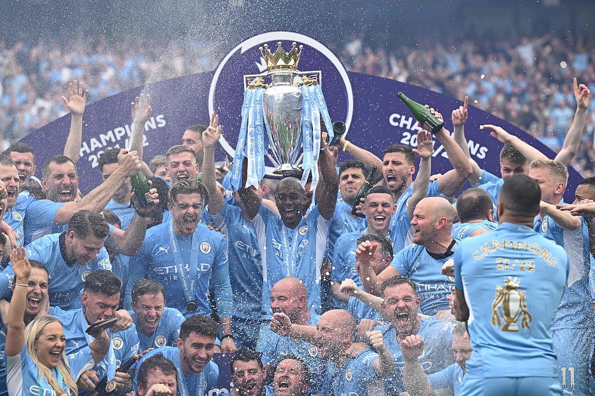 Manchester City's Brazilian midfielder Fernandinho lifts the Premier League trophy as City players celebrate on the pitch at the Etihad Stadium in Manchester, England, on 22 May, 2022