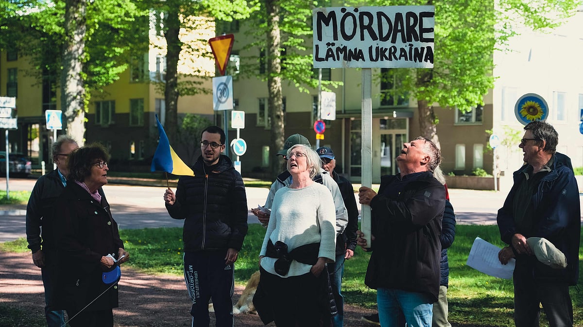 A man holds a sign reading "murders leave Ukraine" during a protest in front of the Russian embassy in Mariehamn, Aland, Finland on 1 June 2022