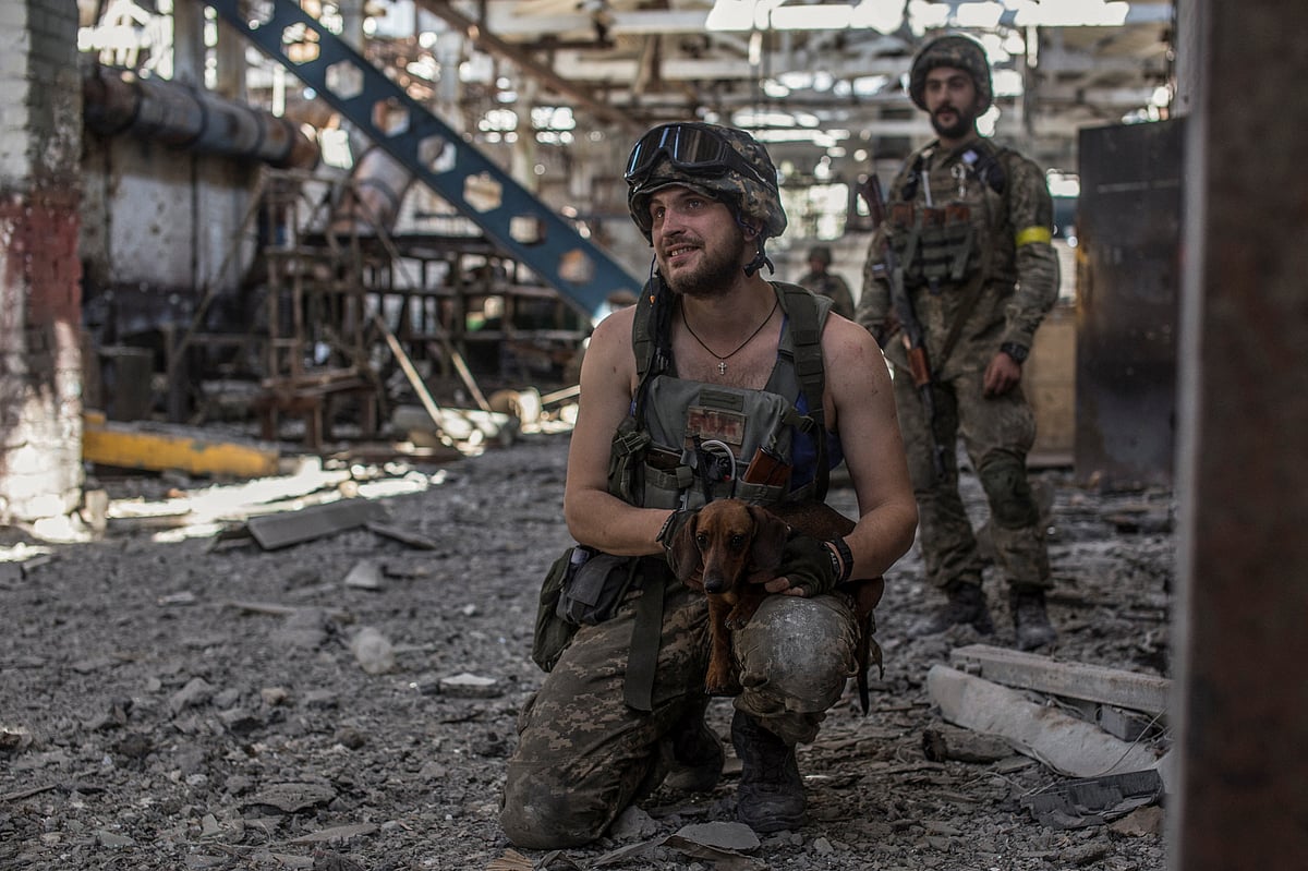 A Ukrainian service member pets a dog in the industrial area of the city of Sievierodonetsk, as Russia's attack on Ukraine continues, Ukraine on 20 June, 2022
