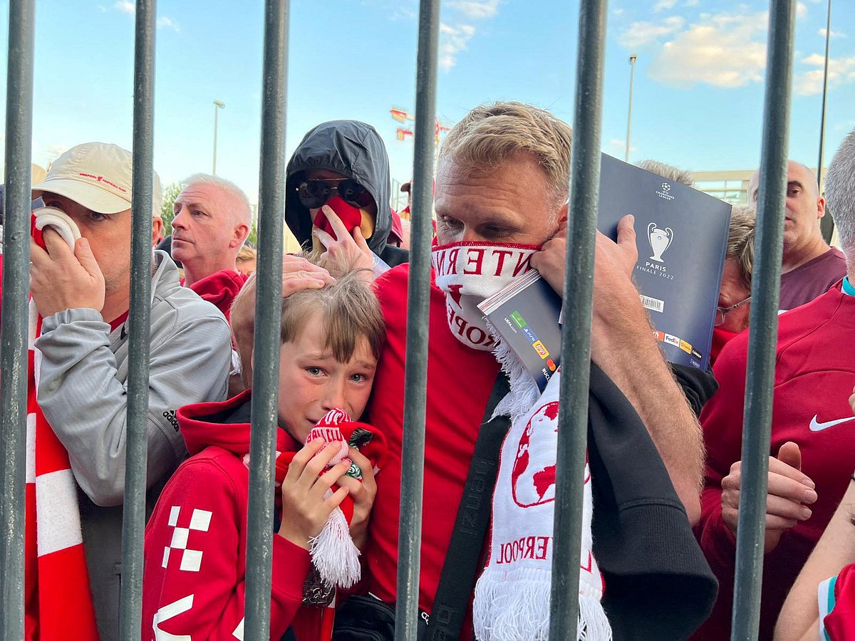Liverpool fans cover their faces after the French police used tear gas while they queue to enter the Stade de France, Paris to watch the UEFA Champions League final on 28 May, 2022
