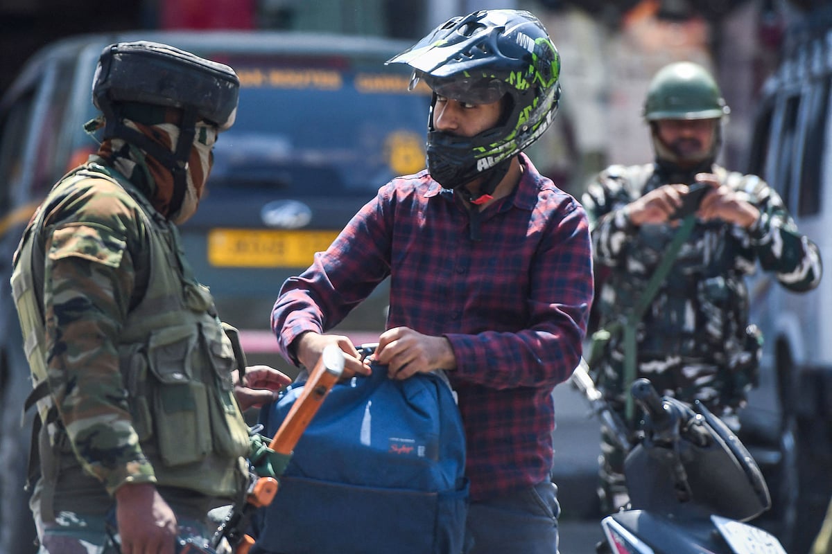 Indian paramilitary troopers check a man's bag during a random search along a street in Srinagar on 2 June 2022. Suspected rebels shot dead a Hindu bank manager on 2 June in Indian-administered Kashmir, police said, the seventh in a spate of targeted killings in the disputed territory.
