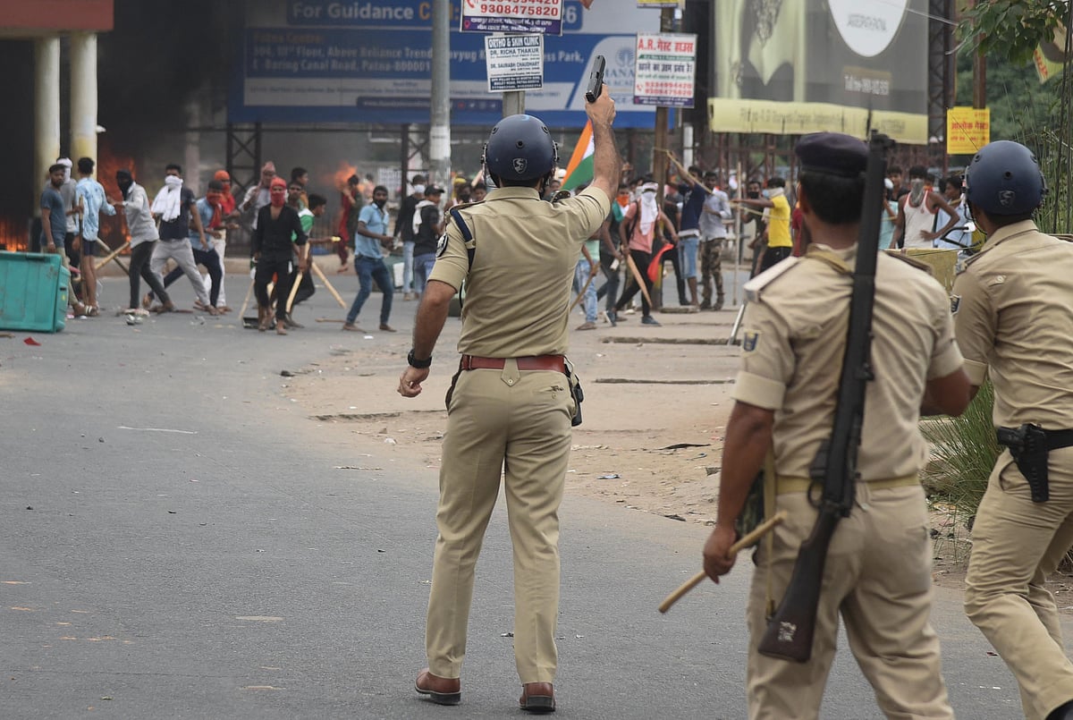 A policeman fires a gun during a protest against "Agnipath scheme" for recruiting personnel for armed forces, in Patna, in the eastern state of Bihar, India on 17 June, 2022