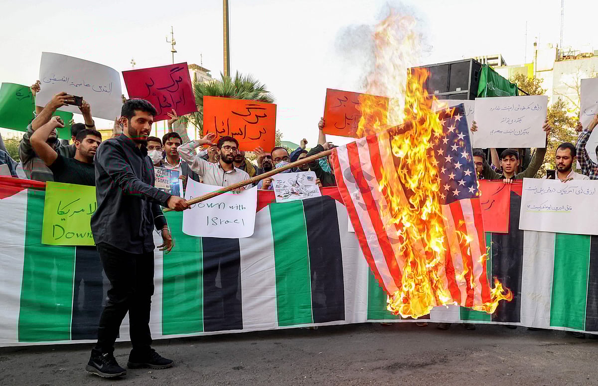 An Iranian student from the Islamic Basiji volunteer militia burns a US flag in the capital Tehran, on 16 July 2022, during a protest against the US President's visits to Israel and Saudi Arabia