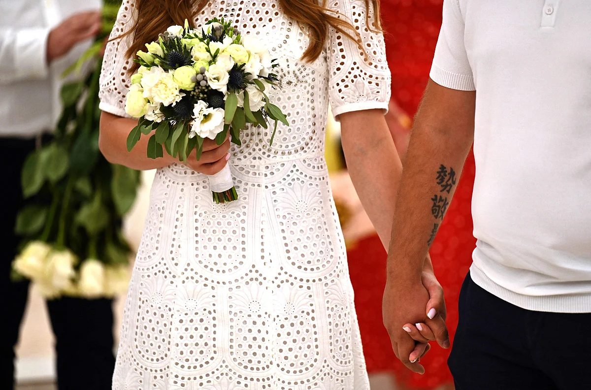 A couple holds their hands during the wedding ceremony in one of the city register offices in Kyiv on 23 July, 2022
