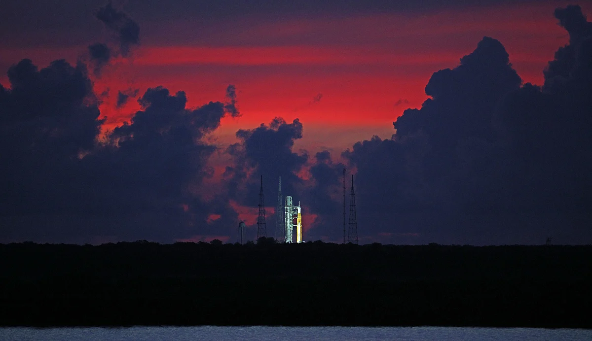 The sky begins to clear before dawn, highlighting the Artemis-1 moon rocket at Launch Pad 39 at the Kennedy Space Center, in this view from Titusville, Florida on 23 August, 2022