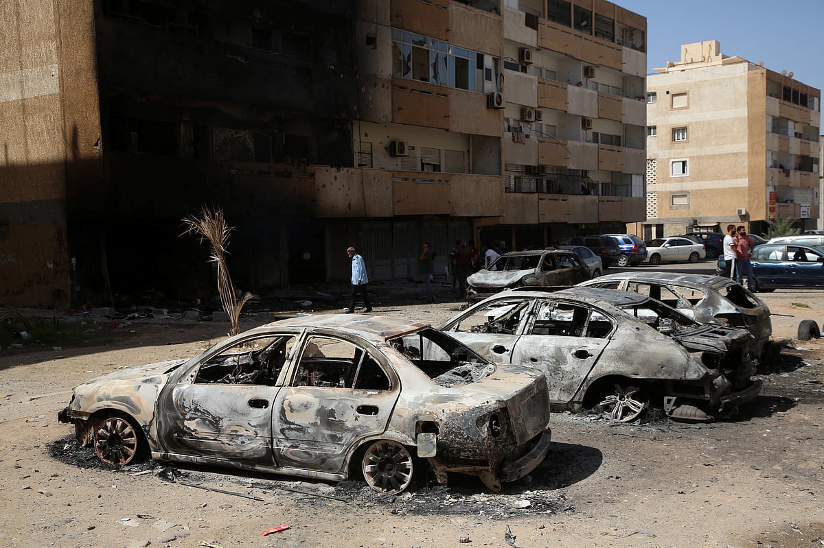 People gather next to burnt cars after yesterday's clashes in Tripoli, Libya August 28, 2022.