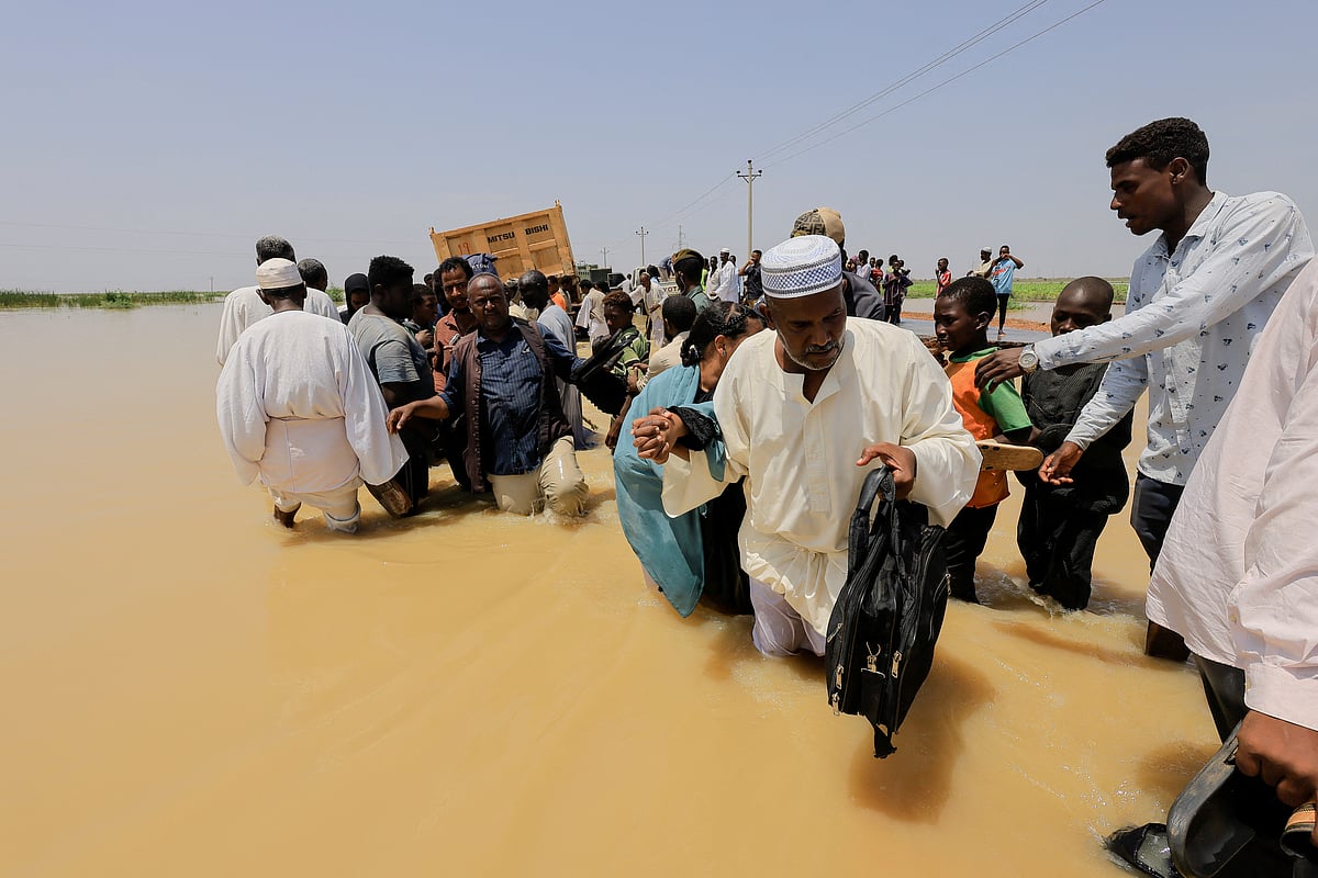 People cross the water during a flood in Al-Managil locality in Gezira state, Sudan, 23 August 2022.