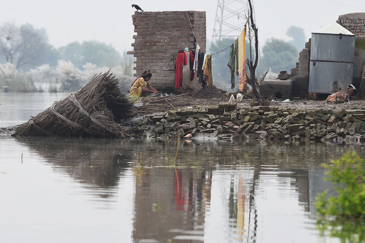 A flood affected woman washes pots at her house damaged by flooed waters in Fazilpur area following heavy monsoon rains in Rajanpur district, Punjab province, on 3 September, 2022