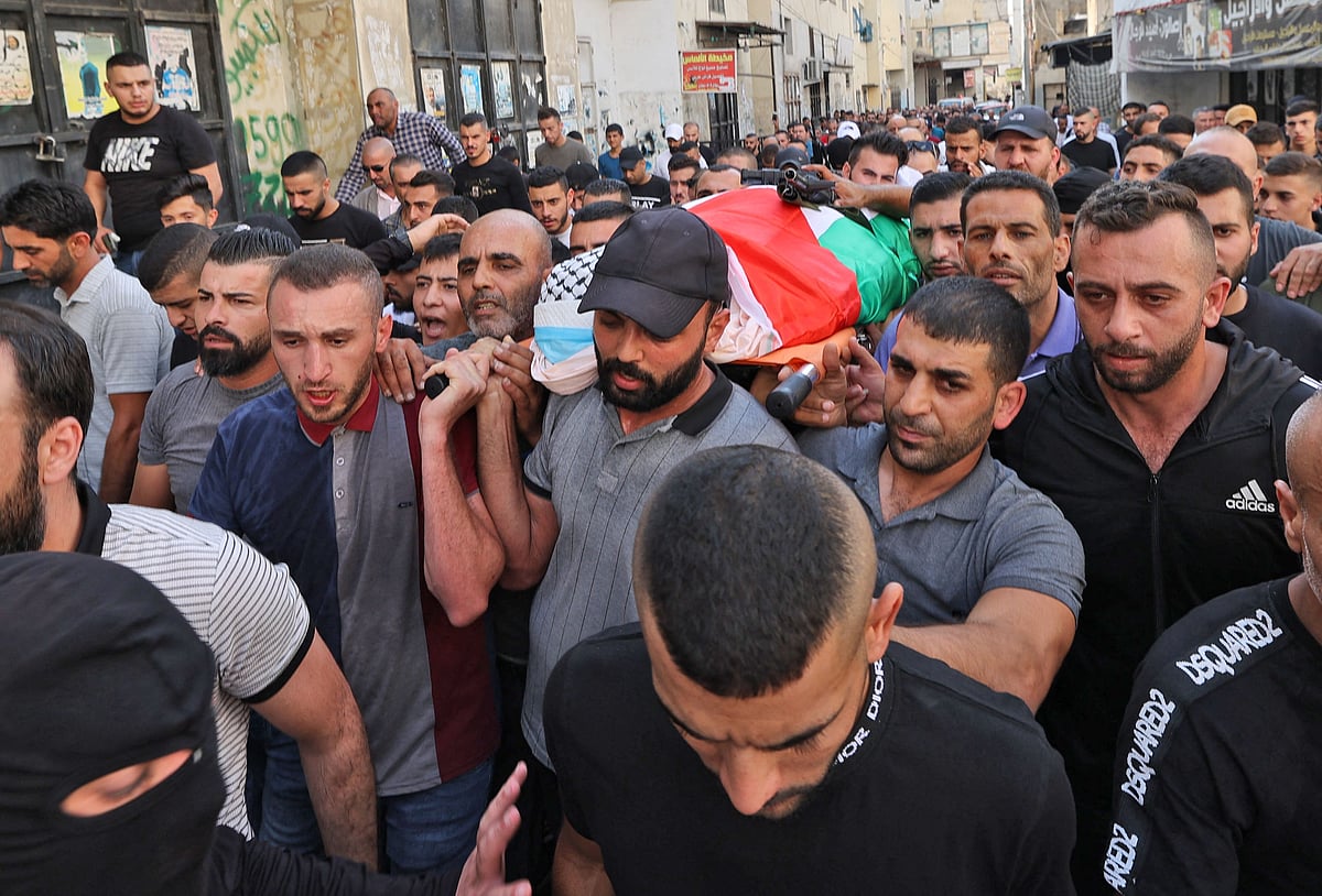 Palestinian mourners carry the body of Abdullah al-Ahmad, a doctor killed during an Israeli raid earlier today, during his funeral in the Jenin refugee camp, near the West Bank city of the same name, in the occupied West Bank, on 14 October, 2022