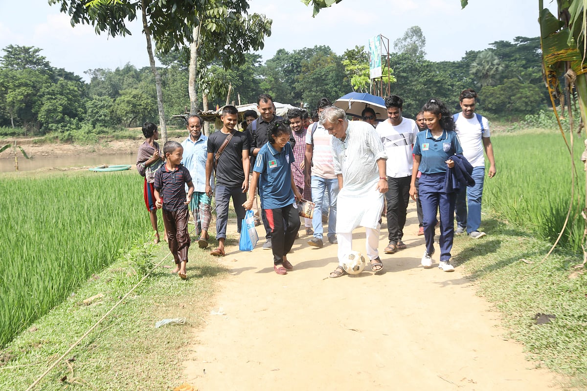 Footballers Mariya Manda and Sanjida Akter share a light moment with Kishor Alo editor Anisul Hoque, having fun with a football as they walk towards the Kalsindur Primary School from Mandirgona in Mymensingh