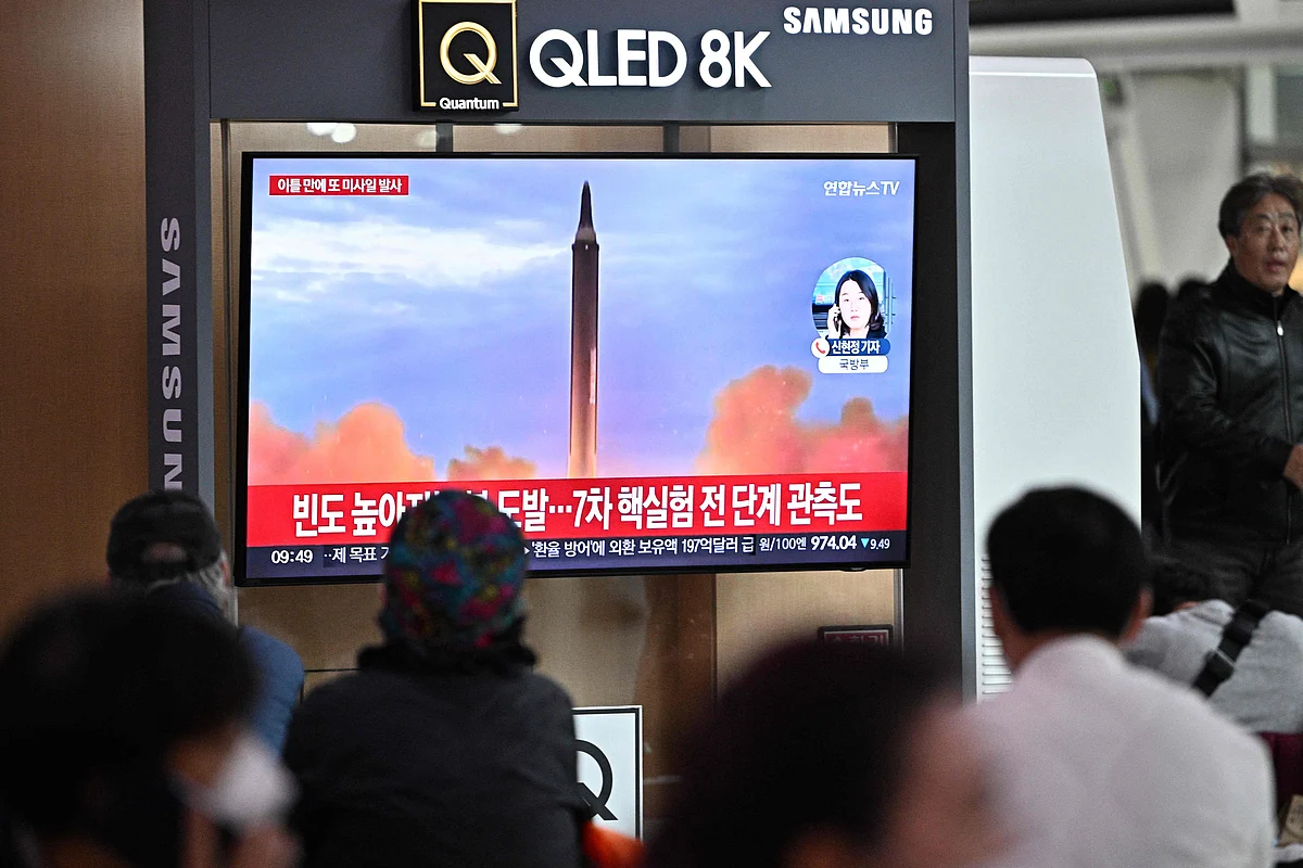 People sit near a television showing a news broadcast with file footage of a North Korean missile test, at a railway station in Seoul on 6 October, 2022