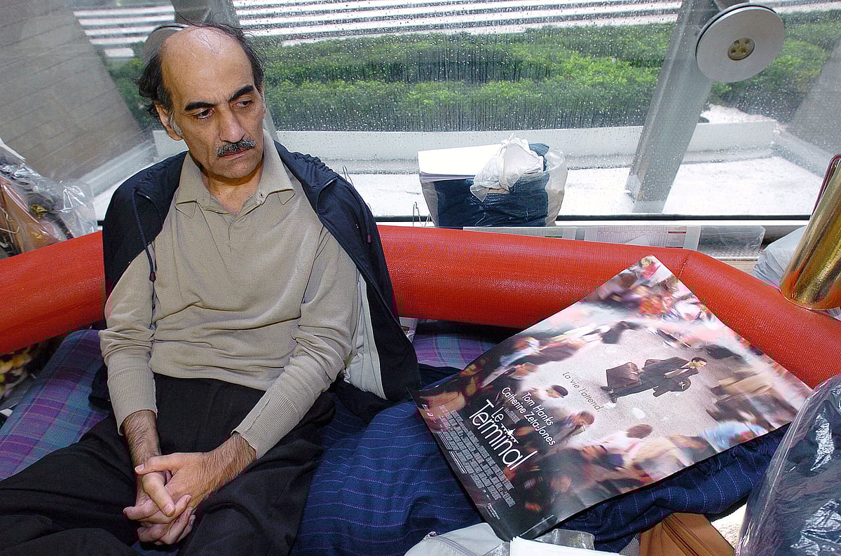 In this file photo taken on 12 August, 2004 Mehran Karimi Nasseri looks at a poster of the movie inspired by his life, in the terminal 1 of Paris Charles De Gaulle airport. Mehran Karimi Nasseri, a political refugee who lived over 18 years in Paris' Roissy-Charles de Gaulle airport and inspired director Steven Spielberg's "The Terminal", died, aged 77, at Roissy-Charles de Gaulle airport's terminal 2F, as reported to AFP by airport officials.