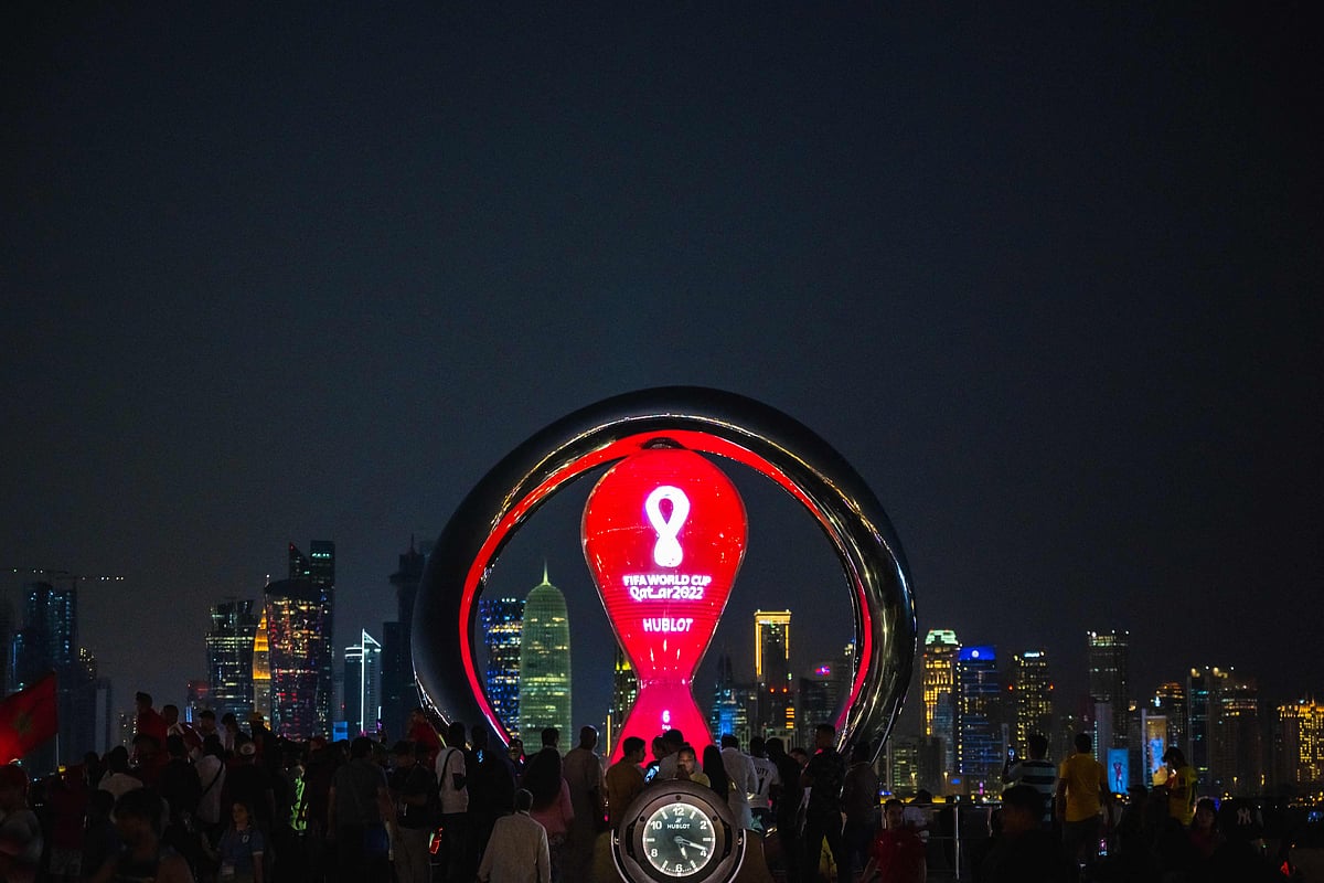 People gather for photos around the World Cup countdown clock in Doha on 14 November, 2022, ahead of the FIFA World Cup 2022