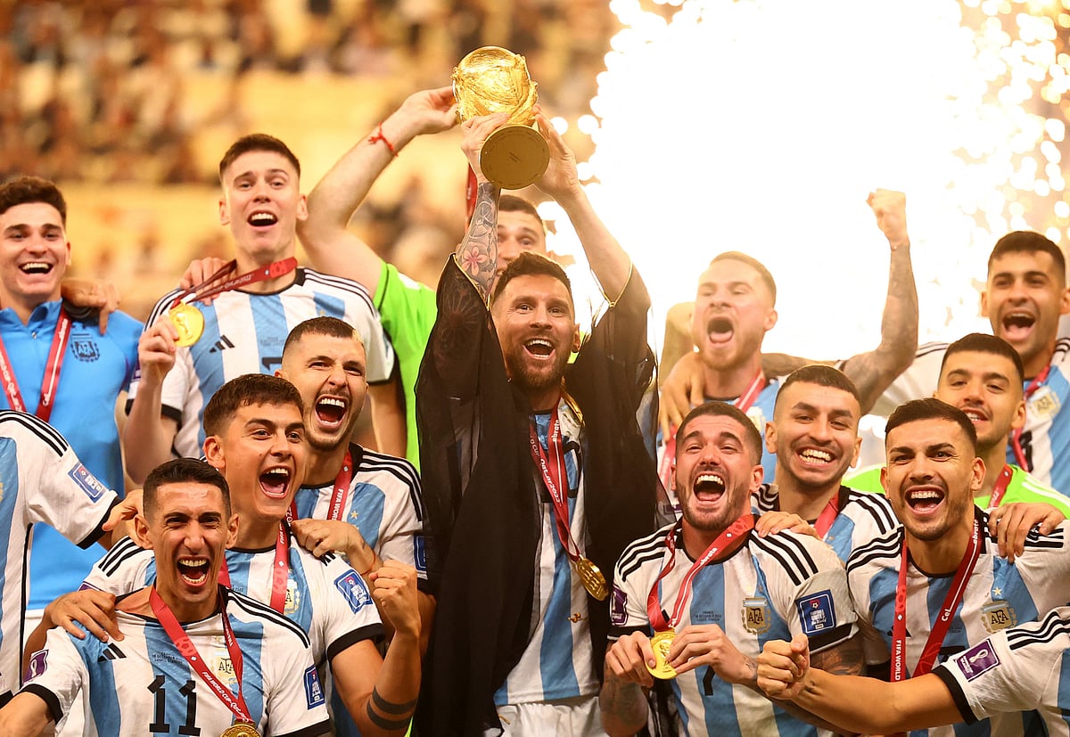 Argentina's Lionel Messi lifts the World Cup trophy alongside teammates as they celebrate after winning the World Cup
