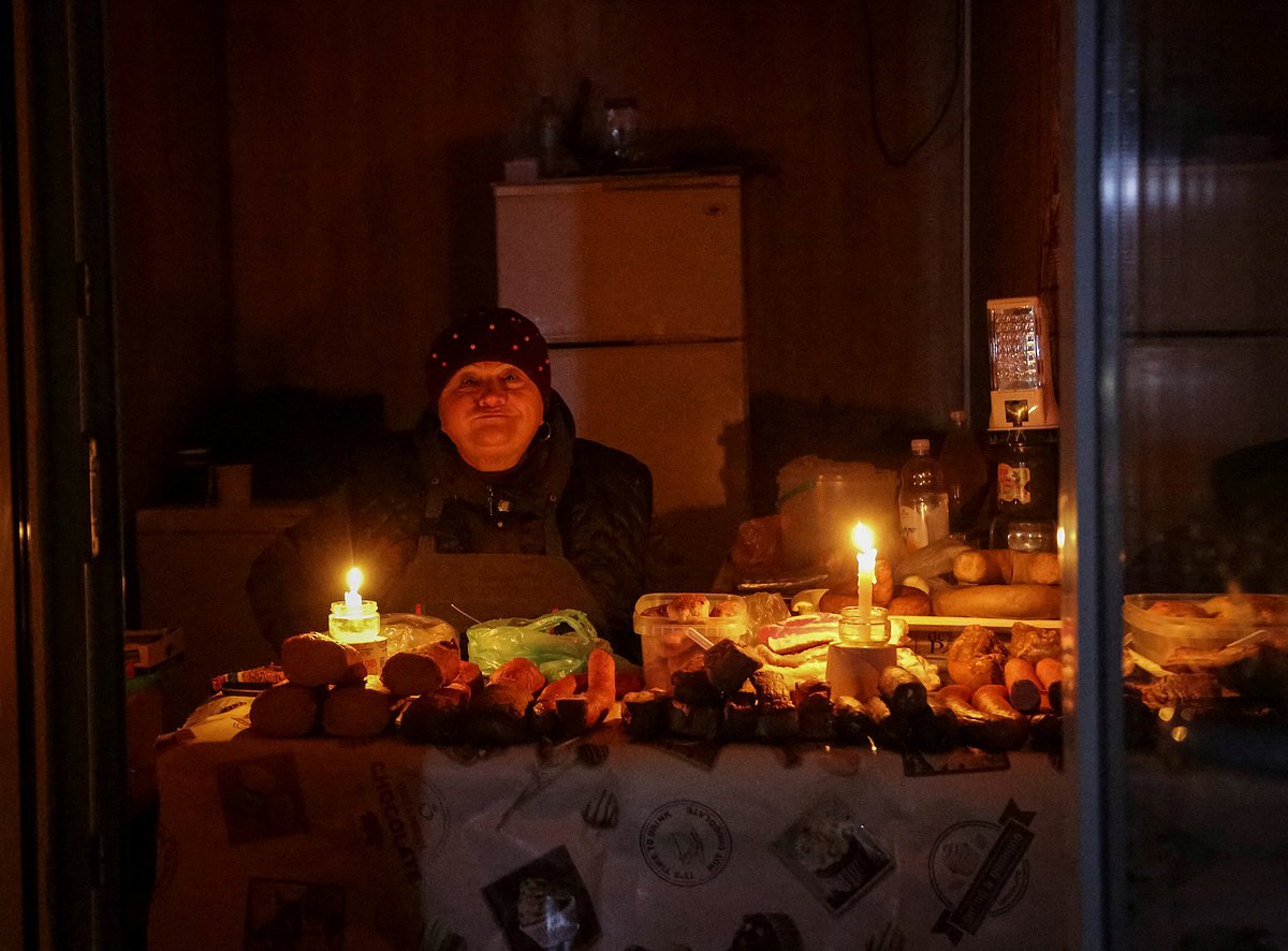 A vendor waits for customers in a small store that is lit with candles during a power outage after critical civil infrastructure was hit by Russian missile attacks, as Russia's invasion of Ukraine continues, in Odesa, Ukraine 5 December, 2022.