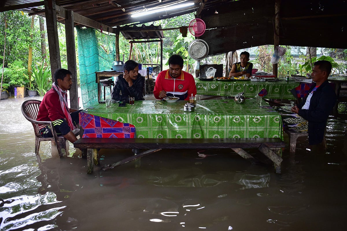 In this photo taken on December 18, 2022, residents eat at a flooded restaurant following heavy rains in the southern Thai province of Narathiwat