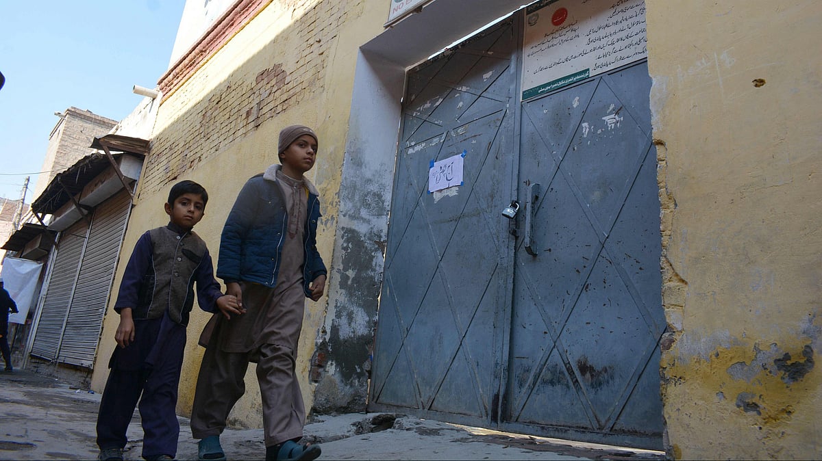 Children walk past a locked school gate after Taliban militants seized a police station in Bannu on 20 December 2022, as authorities ordering schools in the area to close out of fear more kidnappings.