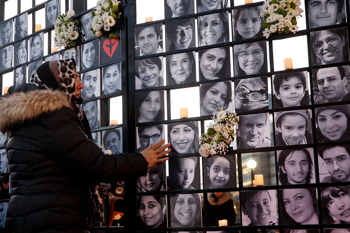 In this file photo taken on January 8, 2022, a woman touches victims' portraits as mourners attend an outdoor vigil for the victims of Ukrainian passenger jet flight PS752, which was shot down two years ago over Iran, in Toronto, Ontario, Canada