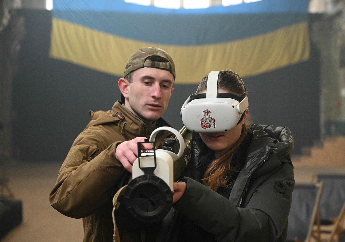A girl holds an anti-tank missile system as she uses a VR headset during an interactive exhibition "Weapons of Victory" where samples of the different anti-tank weapons, including NLAW and Javelin, are shown in Lviv on 28 December, 2022