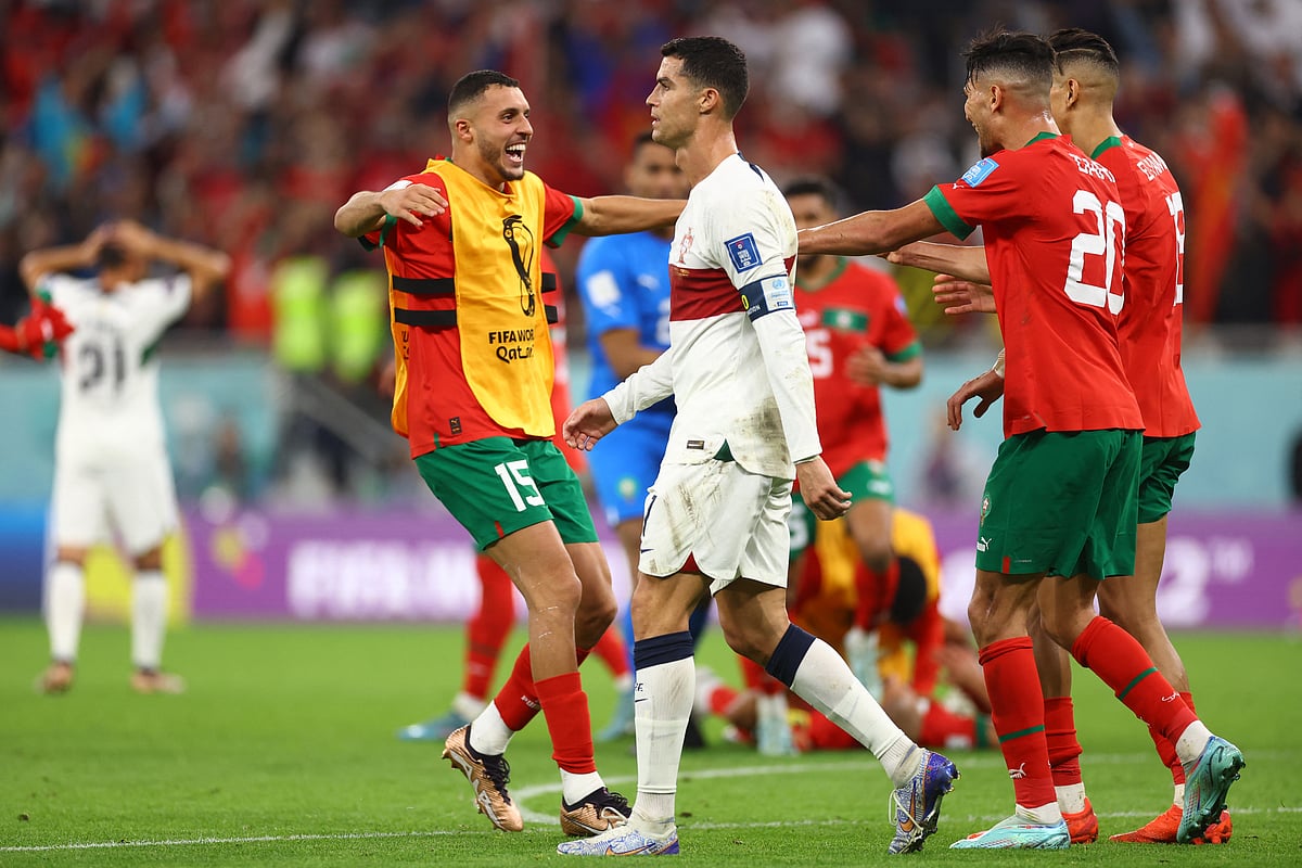 Portugal's Cristiano Ronaldo looks dejected after being eliminated from the World Cup as Morocco players celebrate qualifying for the semi finals