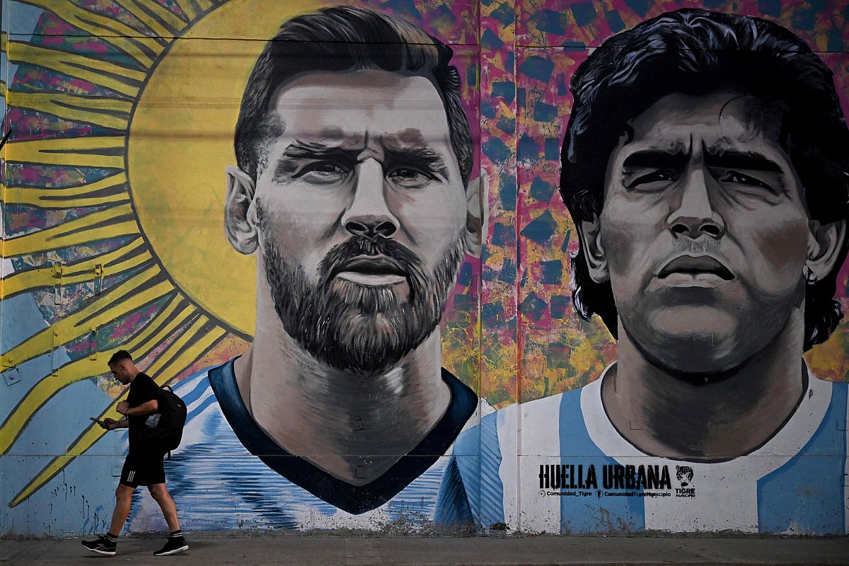 A man passes by a mural depicting Argentine football stars Lionel Messi and late Diego Maradona in the eve of Qatar 2022 World Cup final football match between Argentina and France in Buenos Aires, on 16 December, 2022