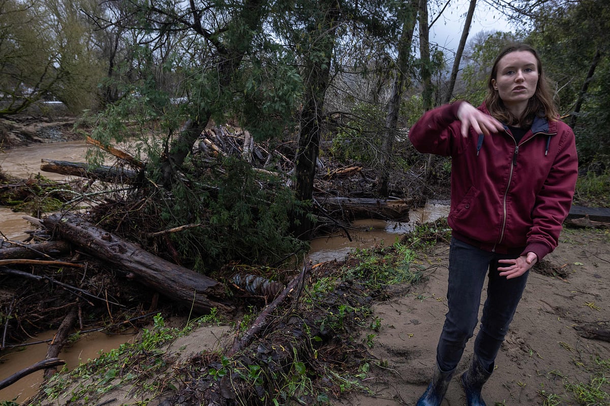 Amberlee Galvin stands next to the normally tiny Zayante Creek, now clogged with trees that piled up and caused additional flooding in Felton, California, on January 14, 2023 as a series of atmospheric river storms continue to cause widespread destruction across the state