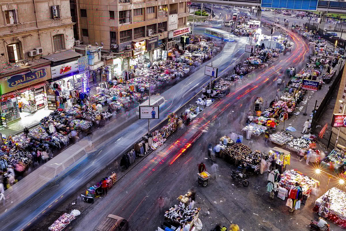 This file long-exposure picture taken on October 24, 2022 shows a view of pedestrians at a street market in Attaba Square in the centre of Egypt's capital Cairo. Limited bank withdrawals, rationed bags of rice and advertised health benefits of chicken feet all spell crisis in Egypt, where a worsening economy chokes households