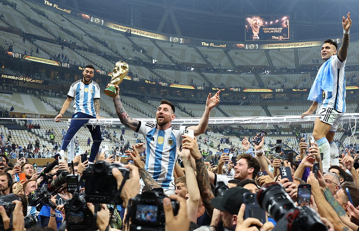 Argentina's Lionel Messi celebrates with the trophy after winning the FIFA World Cup as Lautaro Martinez is sat atop the frame of a goal