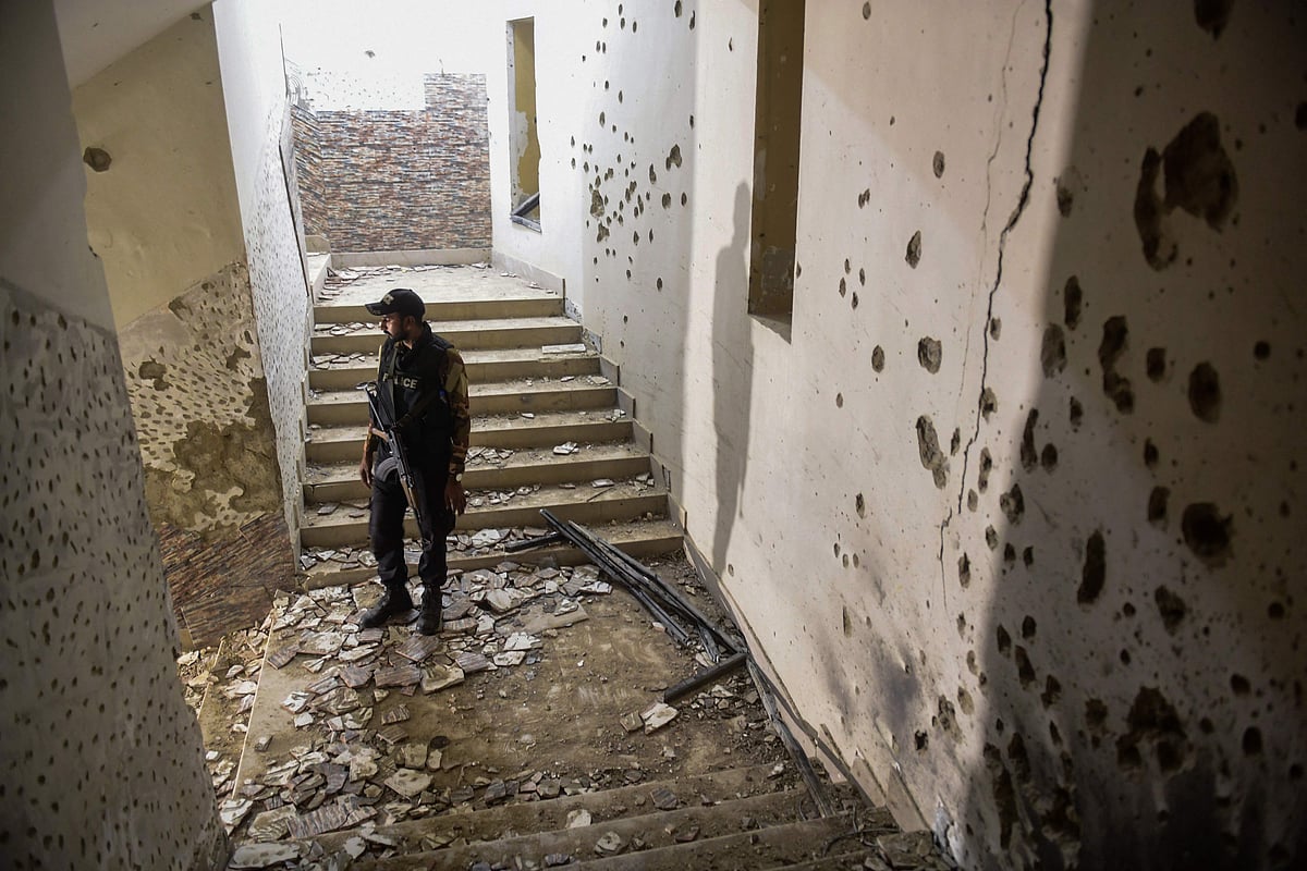 A police officer stands next to a bullet-riddled wall as he inspects a police compound after taking control of the building, following an attack by Pakistani Taliban fighters, in Karachi on 17 February, 2023.
