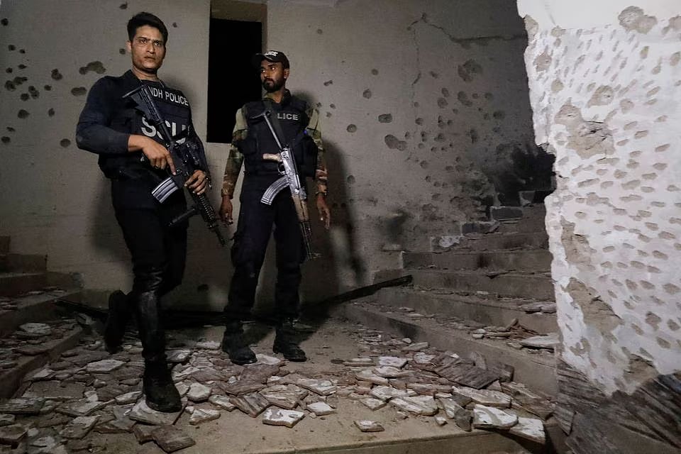 Police officers stand in the aftermath of an attack on a police station in Karachi, Pakistan on 17 February, 2023.