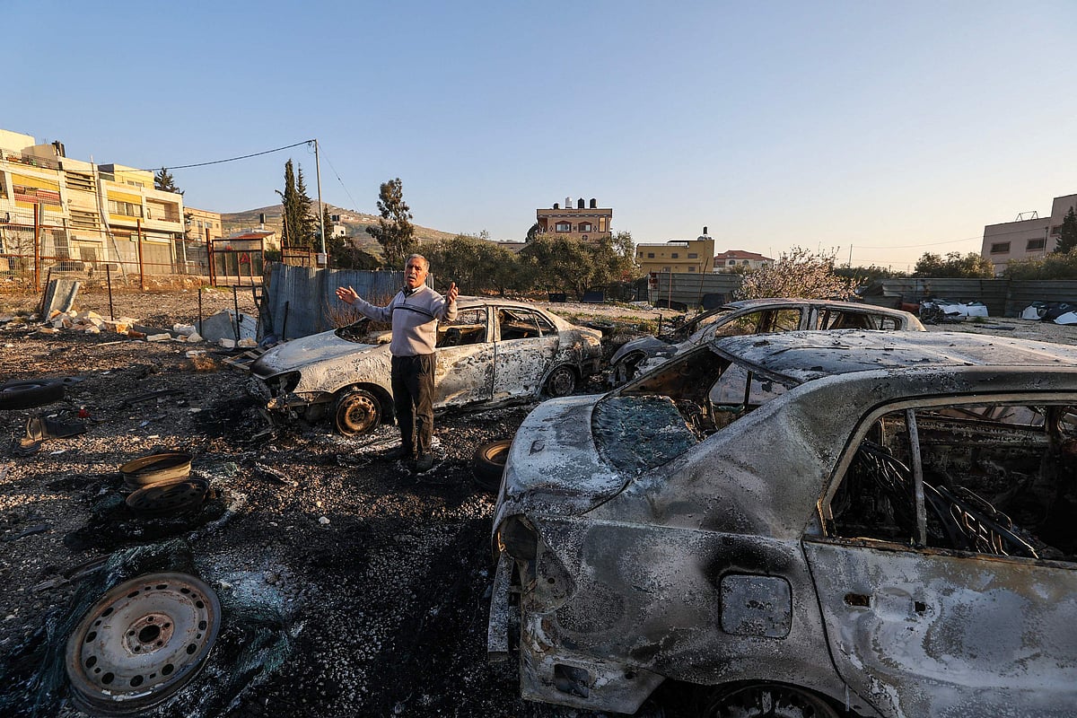 A Palestinian man checks torched cars in Hawara, in the occupied West Bank, on 27 February, 2023