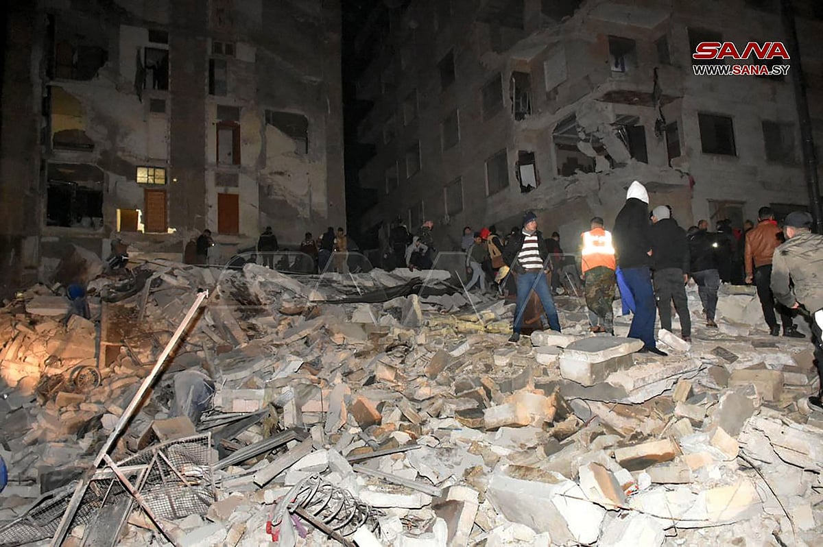 In this handout photo taken by Sana news aganecy in Hama, Syria on 6 February, 2023, rescuers search for victims from an eight-storey building that collapsed after an 7.8-magnitude earthquake in southern Turkey