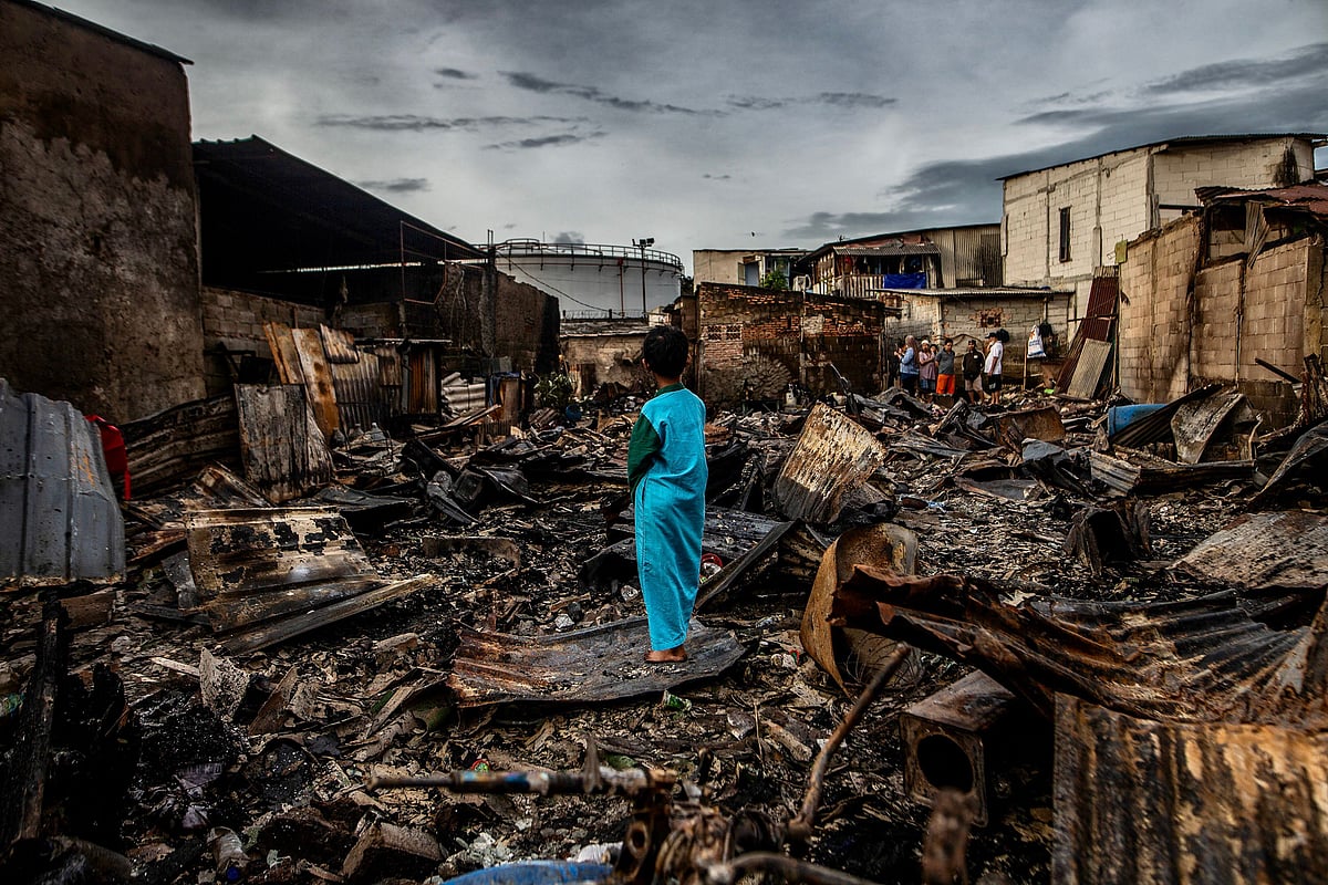 A boy stands in the remains of a burnt house in a residential area in Plumpang, north Jakarta on 4 March, 2023, after a fire at a nearby state-run fuel storage depot run by energy firm Pertamina.